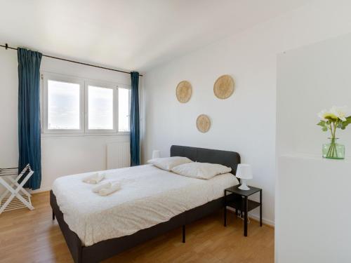 a white bedroom with a bed and a window at Vue sur Paris, Centre Ville in Choisy-le-Roi