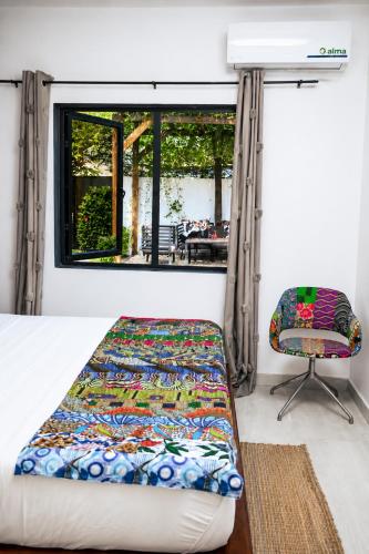 a bed and a chair in a room with a window at Ahomé Guest house & Lounge in Lomé