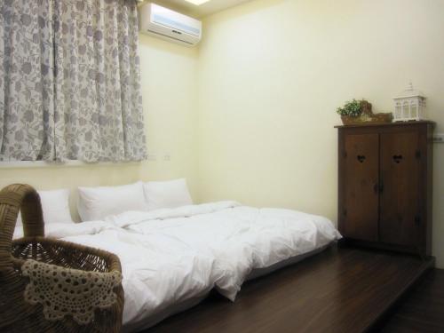 a bedroom with a bed with white sheets and a dresser at Sweet Home 101 in Guangfu