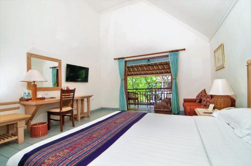 a bedroom with a large bed and a desk at Sativa Sanur Cottages in Sanur