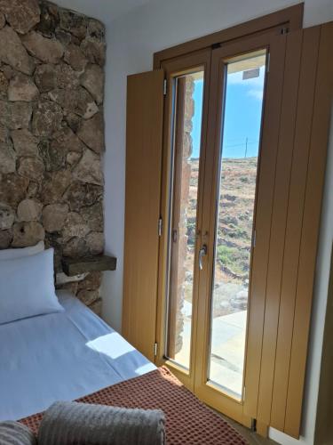 a bedroom with a bed and a sliding glass door at ACHERONAS Residences in Serifos Chora