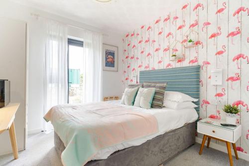 a bedroom with a large bed with pink flamingos on the wall at Porth Beach Hotel in Newquay