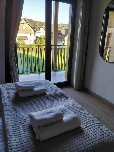 a bedroom with two towels on a bed with a large window at Apartamenty Etno Pieniny in Jaworki