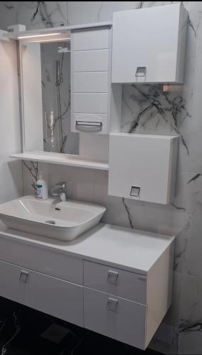 a white bathroom with a sink and a mirror at Villa Aqua Tuzla in Drenovik