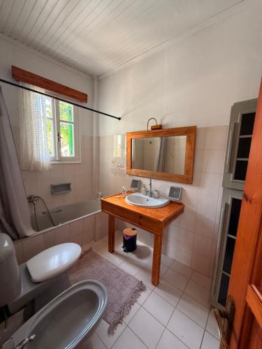 a bathroom with a sink and a mirror and a tub at Christina's Sea View House in Yénion
