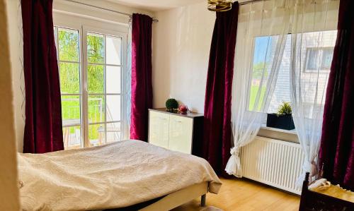 a bedroom with a bed and two large windows at CK Apartment in Oberhofen am Irrsee