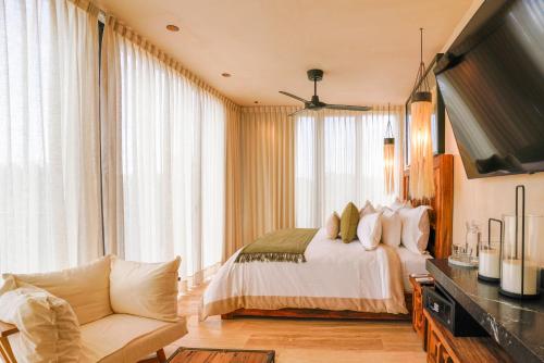 a bedroom with a bed and a tv and a couch at Trobbu Boutique Collection Riviera Maya - All inclusive in Tulum