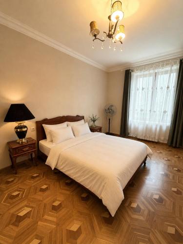 a bedroom with a large white bed and a chandelier at Nice Apartment in the City Center in Yerevan