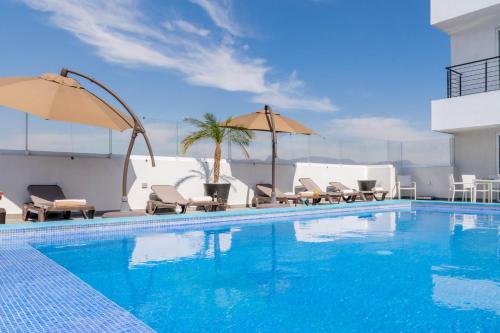 a swimming pool with chairs and umbrellas next to a building at Hotel Stadium Leon in León