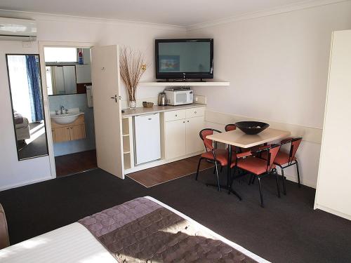 a room with a kitchen and a table with a television at Mornington Motel in Mornington