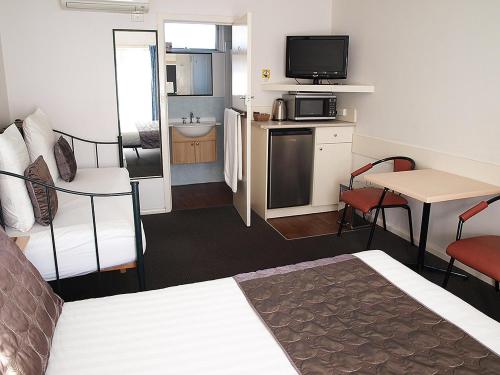 a hotel room with a bed and a kitchen and a bathroom at Mornington Motel in Mornington