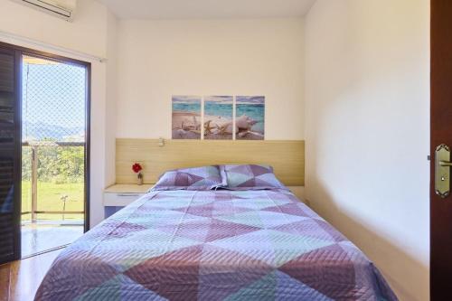 a bedroom with a bed and a large window at CHARMOSO seu apto a apenas 300 mts da rua mais turistica de ubatuba in Ubatuba