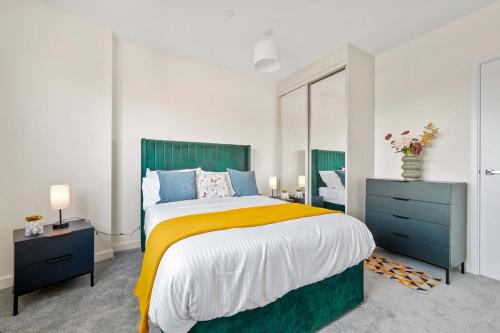 a bedroom with a large bed with a yellow blanket at Modern 2 Bedroom Flat with FREE Parking, Close to Heathrow and Thorpe Park in Staines