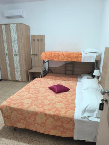 a bedroom with a bed with a purple pillow on it at Pensione Fiorella Rimini in Rimini