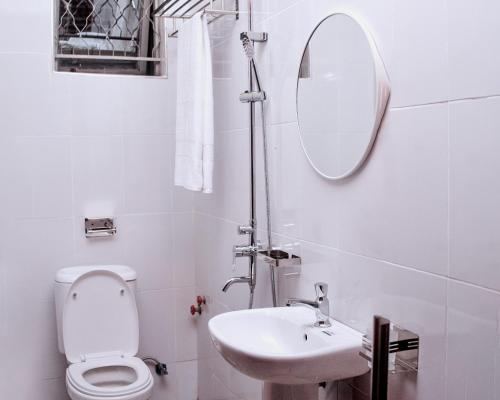 a bathroom with a toilet and a sink and a mirror at Mol Mot Hotel in Gulu
