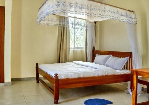 a bedroom with a canopy bed with a window at Mol Mot Hotel in Gulu