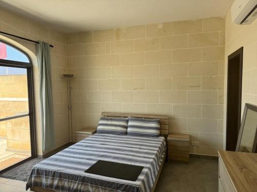 a bedroom with a bed and a large window at Sea Views Penthouse Apartment in Xagħra