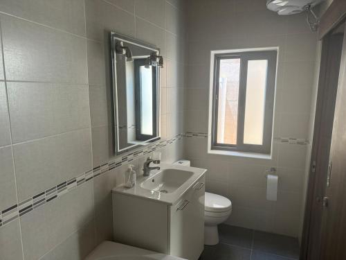a white bathroom with a sink and a toilet at Sea Views Penthouse Apartment in Xagħra