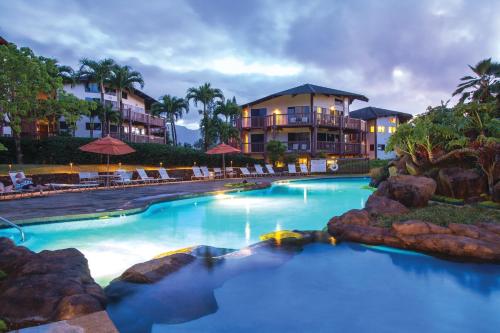a swimming pool with a resort in the background at Ka Eo Kai Resort 2BR Villa in Princeville