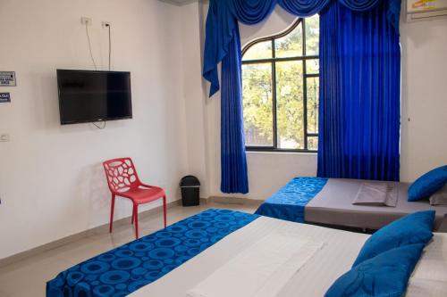 a bedroom with two beds and a red chair and a window at Hotel Perla Azul Girardot in Girardot