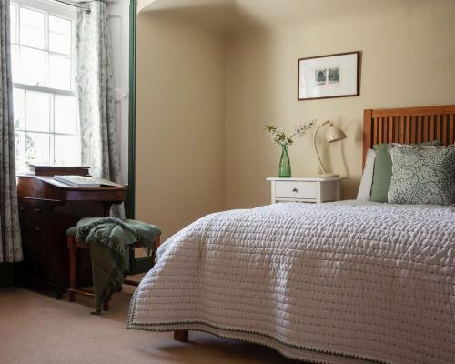 a bedroom with a bed and a desk and a window at Newbyth Garden Cottage in East Linton