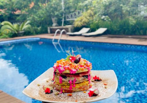 a stack of pancakes on a plate next to a pool at Ankola Hotel in Homagama