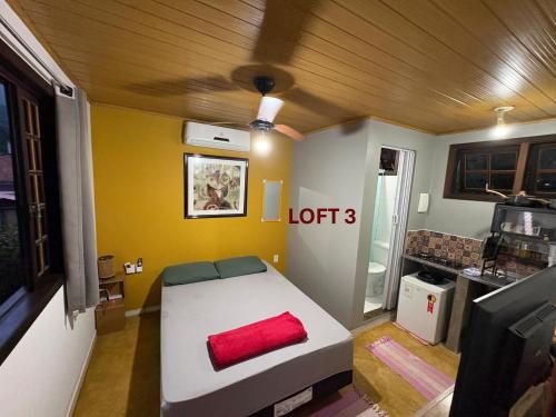 a room with a bed with a red pillow on it at Mi Casa Su Casa Lofts in Abraão