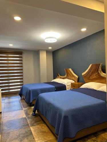 a room with three beds with blue sheets and a window at Hotel La Bikina in Tequila