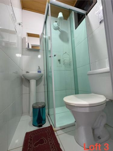 a bathroom with a toilet and a glass shower at Mi Casa Su Casa Lofts in Abraão