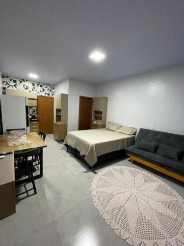 a bedroom with a bed and a couch and a table at Apartamento Açaí in Vilhena
