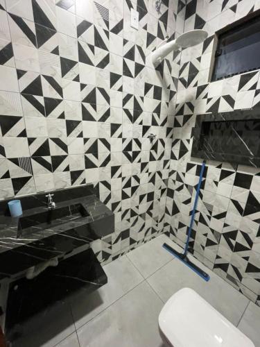 a bathroom with a black and white tiled wall at Apartamento Açaí in Vilhena