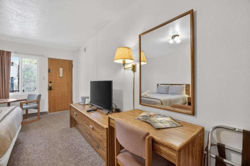 a hotel room with a desk with a bed and a mirror at Eagle Motel Suite 108 in Manitou Springs