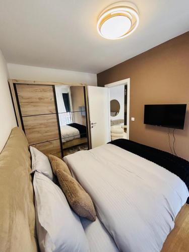 a bedroom with a large white bed with a flat screen tv at Apartman Merry Lux in Vrnjačka Banja