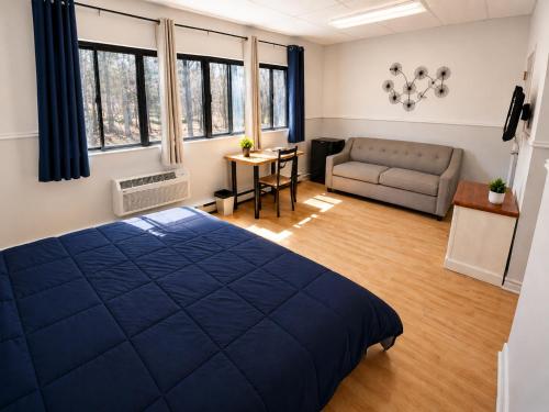 a bedroom with a large blue bed and a couch at Auberge du Mont Rigaud in Rigaud