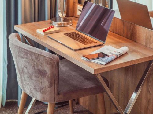 a laptop computer sitting on a wooden desk with a chair at ibis Styles Istanbul Bomonti in Istanbul