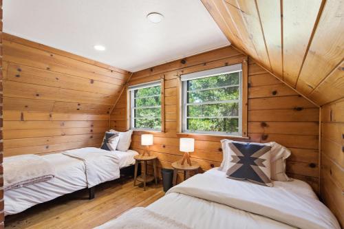 two beds in a room with wooden walls and windows at Harmony Hideaway Hammocks Creek Sounds in Shaver Lake