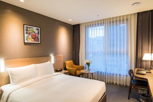 ソウルにあるIBC ホテル トンデムンのベッド、デスク、窓が備わるホテルルームです。