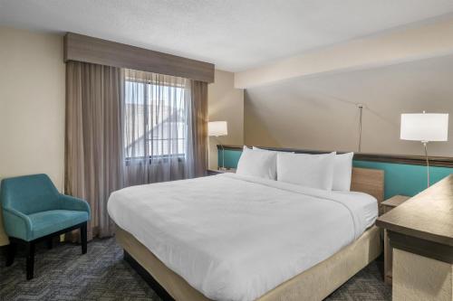 a hotel room with a large bed and a blue chair at Best Western Fishkill Inn & Suites in Fishkill