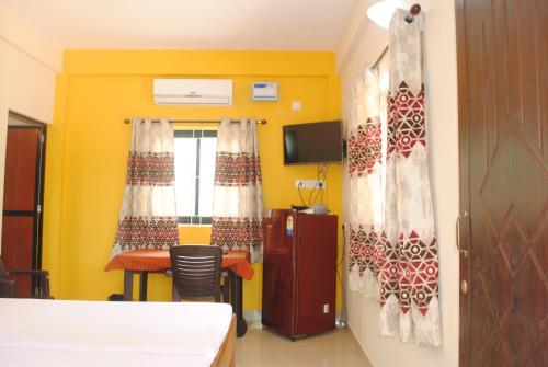 a room with a bed and a table and a tv at Joe And Marietta's Guesthouse in Calangute