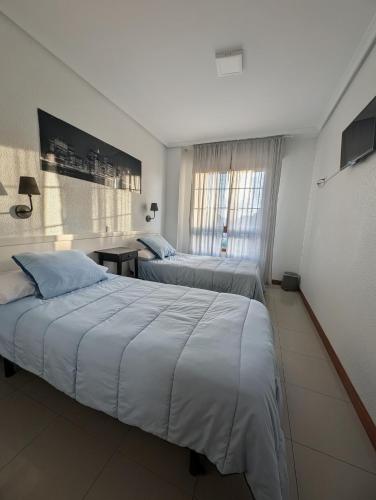 a hotel room with two beds and a window at Alojamiento La Ballena in Santoña