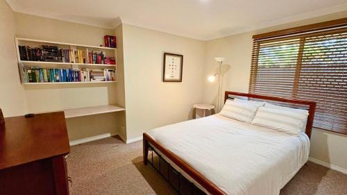 a bedroom with a bed and a desk and a book shelf at Coastal Haven on Sandpiper in Broadwater