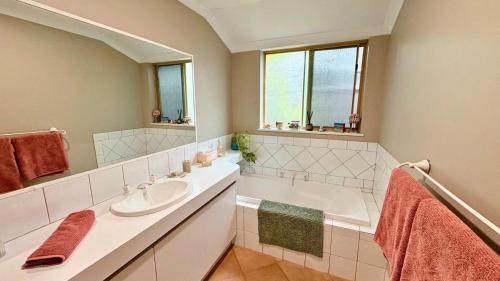a bathroom with a sink and a tub and a mirror at Coastal Haven on Sandpiper in Broadwater