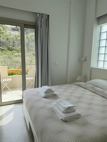 a white bedroom with a bed with towels on it at Casa Horizon in Porto Heli