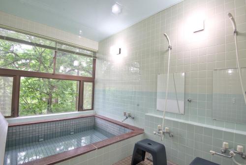 a bathroom with a tub and a window at Wolke Lodge in Shinano