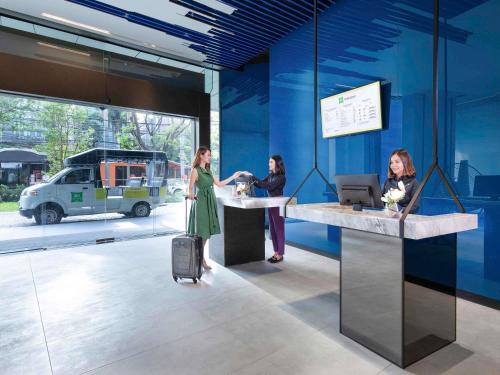 three women are standing at a counter in a building at ibis Styles Bangkok Sukhumvit 4 in Bangkok