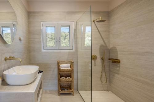 a bathroom with a sink and a glass shower at Villa Ostria in Lixouri