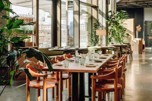 a restaurant with wooden tables and chairs and plants at Locke Copenhagen in Copenhagen
