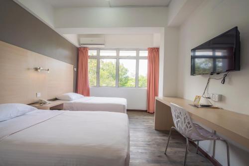 a hotel room with two beds and a television at YMCA Penang in George Town