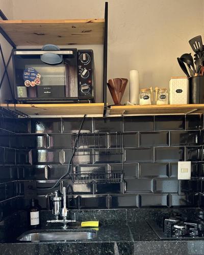 a microwave on a shelf above a kitchen sink at Chalé Lumiar in Santana do Riacho