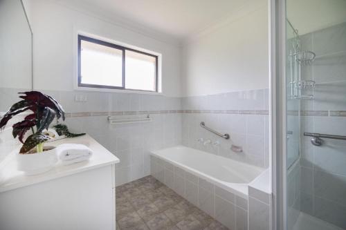a white bathroom with a tub and a sink at Rundle & Salt in Ulladulla